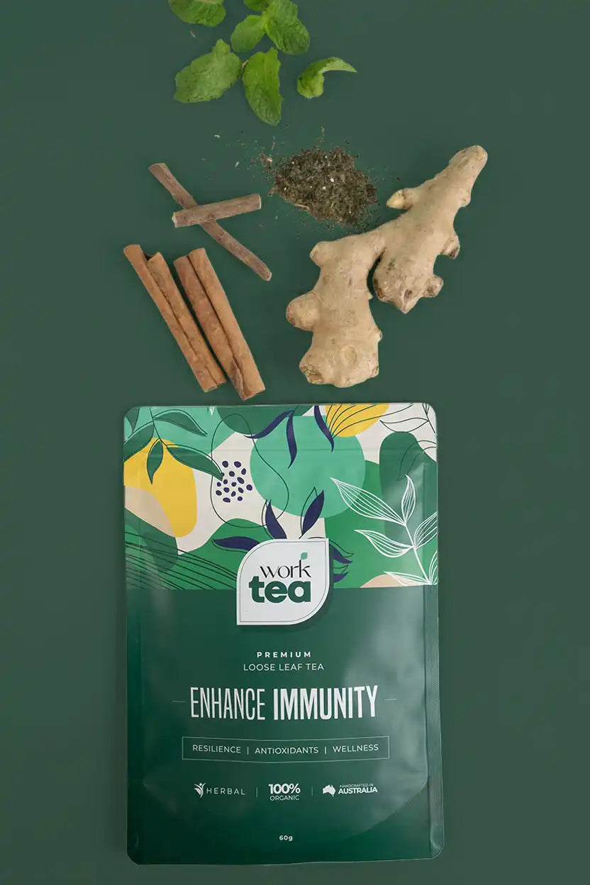 Tea packaging labeled 'Work Tea' with immunity benefits, surrounded by ginger root, cinnamon sticks, and mint leaves on a green background.