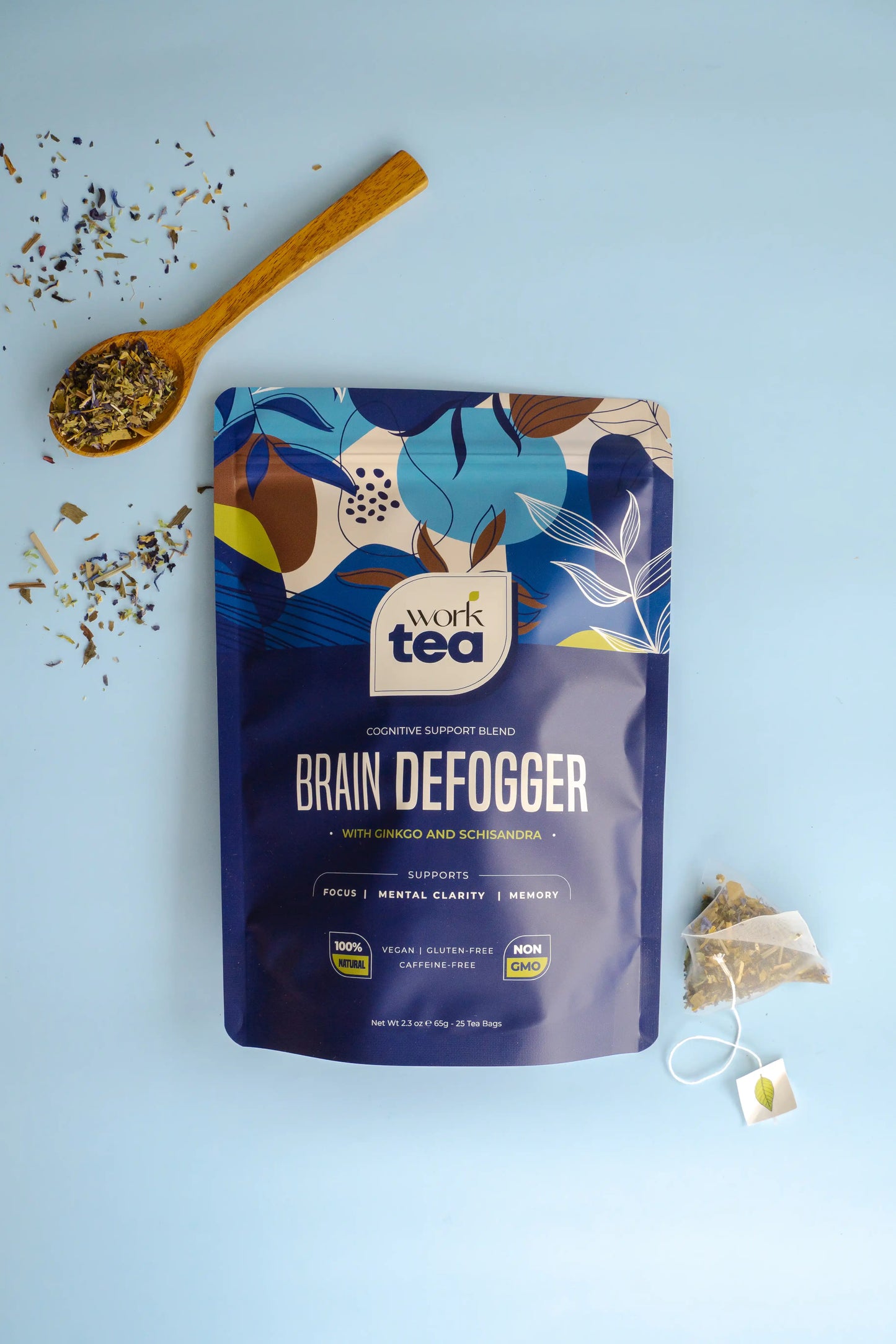 Work Tea 'Brain Defogger' package on a light blue background with tea leaves and a wooden spoon.