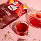 Red tea bag labeled 'Age & Shine' with a glass of red tea and teapot on a pink background
